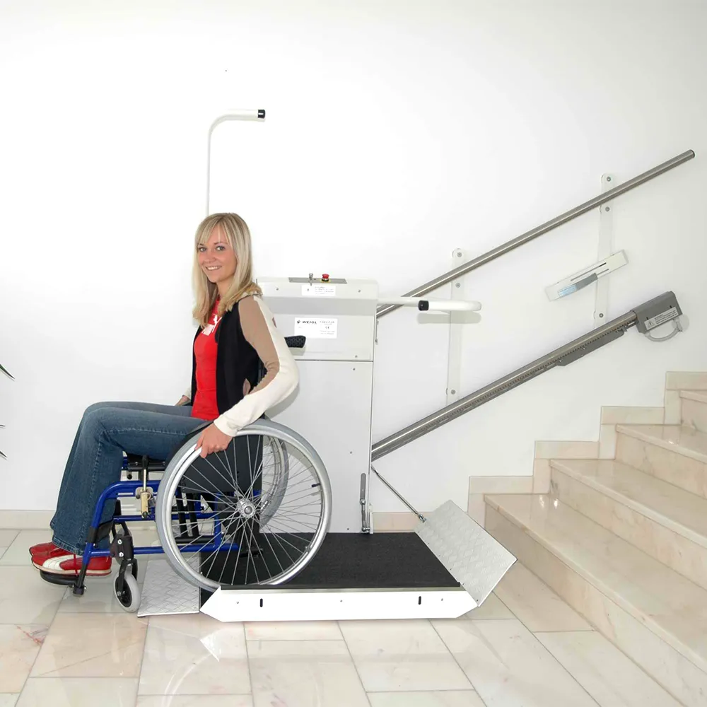 Eine Frau sitzt im Rollstuhl und fährt von der Plattform des Plattformlifts runter. Die Kosten eines Plattformlifts variieren stark.